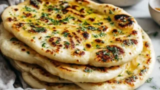 Garlic butter naan stacked and brushed with melted butter and herbs